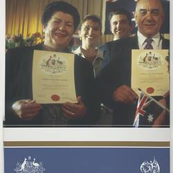 Smiling woman and man hold up certificates. People and partial Australian flag behind. Text below.