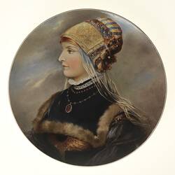 Colourful wall plate with handpainted depiction of a lady in rich clothes.