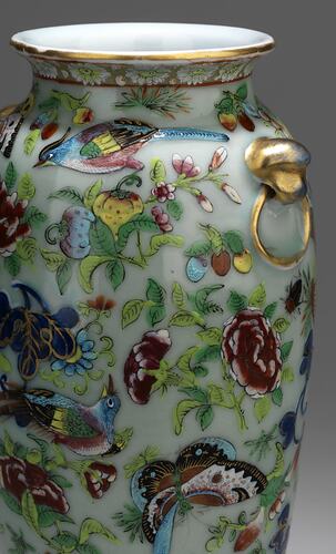 Detail of urn-shaped vase with decorative birds, butterflies, flowers, foliage in blues, gold, greens, reds.