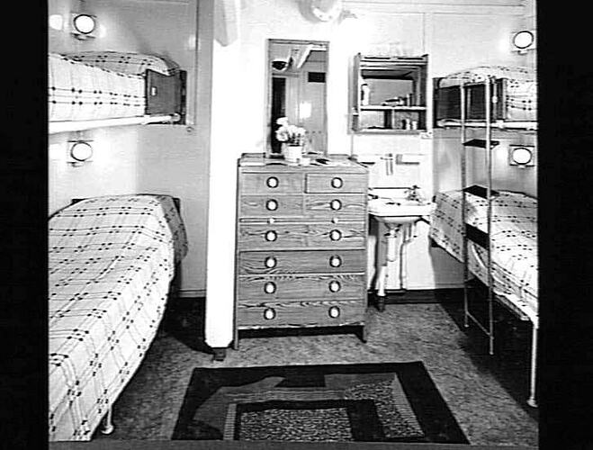 Ship interior. Bunk beds on right and left. Chest of drawers in centre.