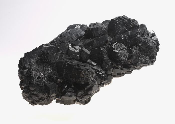 Blocky black crystals forming a rock sample.
