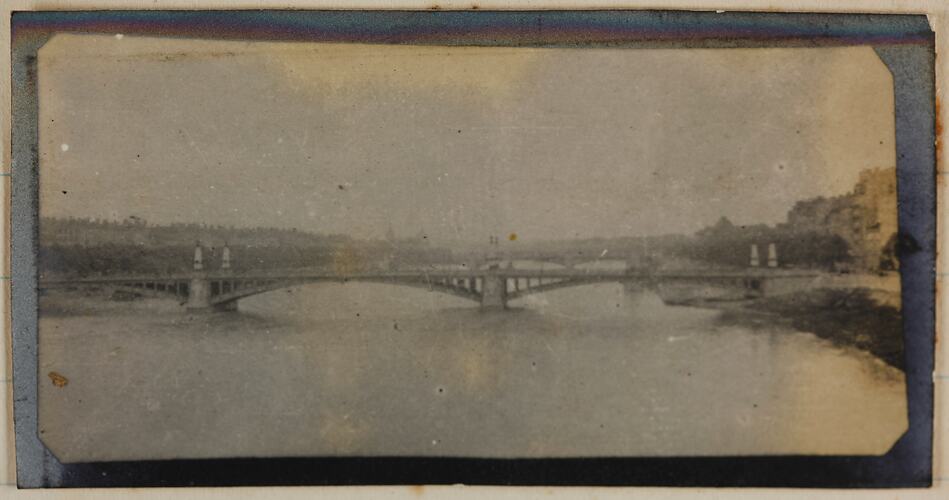 View of a bridge over a river; on the right bank is a township.