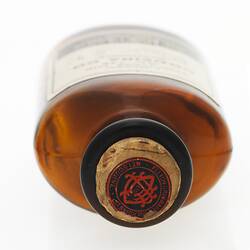 Top of round dark brown bottle with white label visible on front.