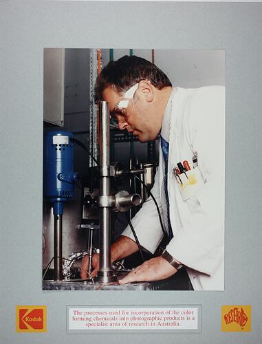Man in labcoat and goggles adjusting equipment.