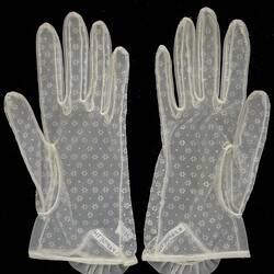 Wrist length gloves made from soft while net with floral pattern. Palm side up.