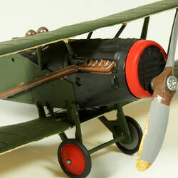 Dark green aeroplane model with red trim. Front three quarter detail view of engine and propeller.