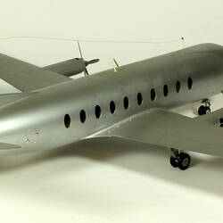 Silver model aeroplane with two propellers on each wing. Back view.
