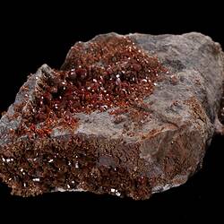 Red-orange crystals on grey rock.