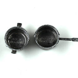 Two toy silver pots, top view.