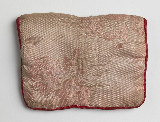 Back of pale pink silk envelope-style pouch with red trim.