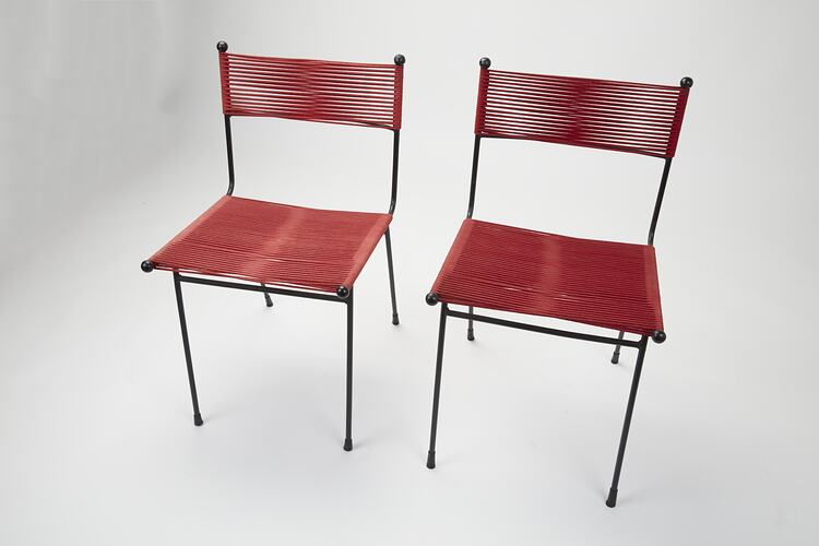 Two metal chairs strung with red cord seats and back sections. Top left view.