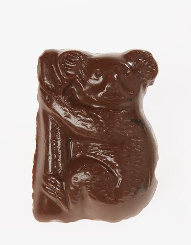 Brown painted plaster model of chocolate koala holding onto a tree.