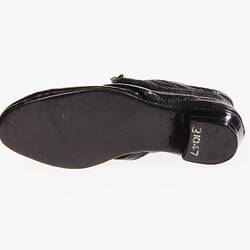 Miniature hand-sewn black leather shoe with black sole. View from below.