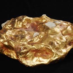 Gold nugget replica with grey bits embedded in it.