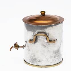 Miniature coffee urn made from silver and copper. Brass handle. Copper tap and lid with knob. Side view.