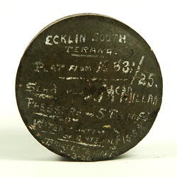Black disc with white handwritten inscription.