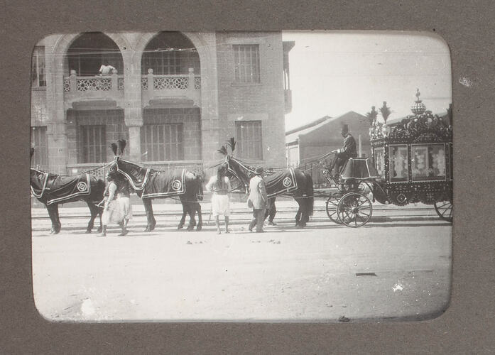 Carriage being drawn by six horses near building.