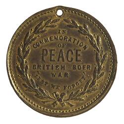 Medal with wreath framing central text. Hole at top.