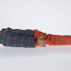 Right profile of laying doll. Red pants, blue top, short brown hair.
