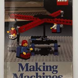 Front cover with LEGO build. Four red carousel-like arms hold LEGO figures, grey base. Text above and below.