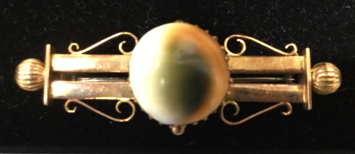 Double bar 15 carat gold brooch with central round operculum.