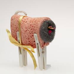 Toy sheep made from folded orange dishwashing sponge, steel wool ball, matches, white pegs.
