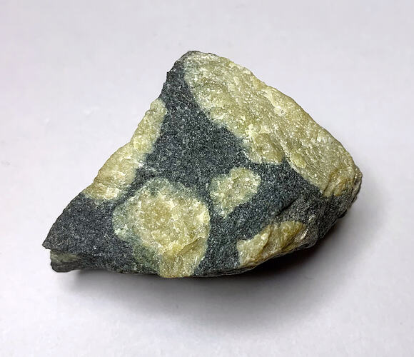 Green-black formation with yellow crystal-like inclusions.