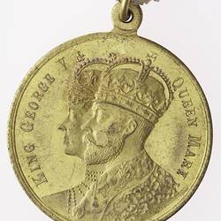 Round gold coloured medal with profile of a crowned man and woman with text and red, white and blue ribbon.