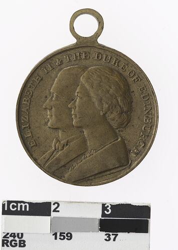 Round medal with profile of a man and woman, text surrounding.