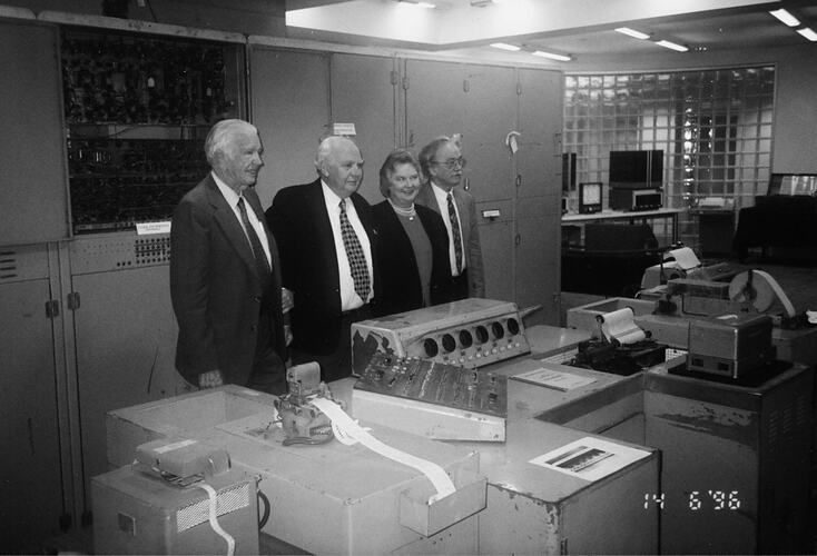 Three men and woman surrounded by computer machinery.