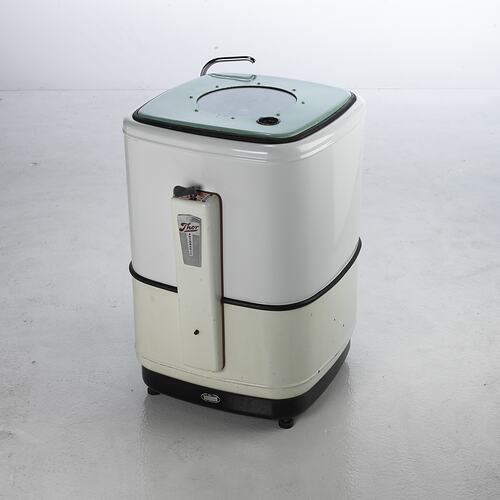 Rectangular, box-shaped washing machine. Rounded edges, white enamel coating and green lid.