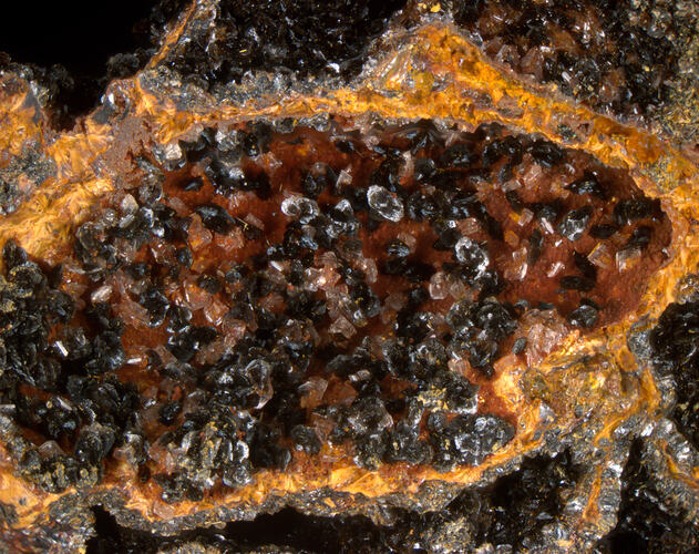 Crystals filling a curved rock surface, shades from clear to brown.