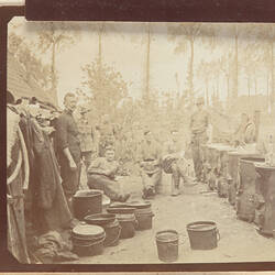 Group of servicemen outside with buckets and row of large cylindrical objects.