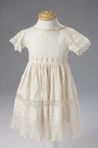Short sleeved white cotton and lace girls dress. Detailed band at waist.