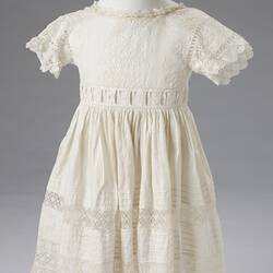 Short sleeved white cotton and lace girls dress. Detailed band at waist.