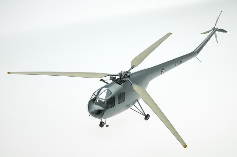Metal model helicopter painted silver with three propellers and three wheels.