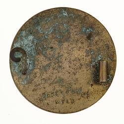 Back of a round metal badge with no pin,