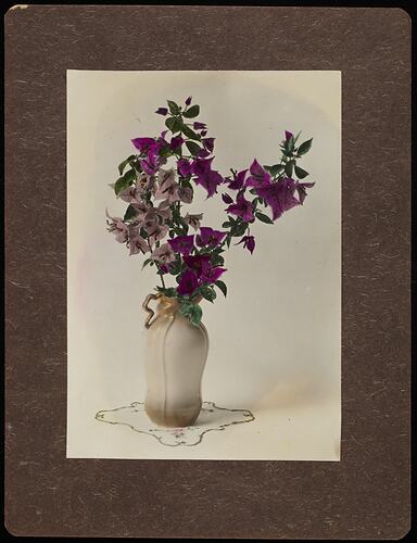 Still life of purple flowers in a white vase.