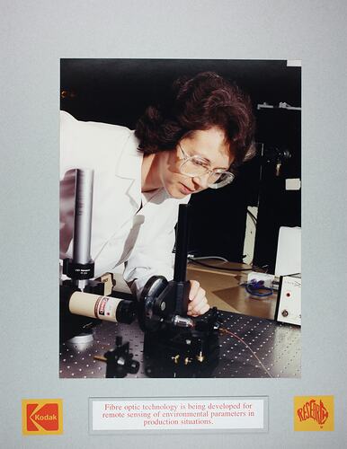 Woman in laboratory monitoring fibre optic equipment.
