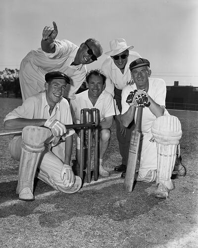 Five men in cricket clothing posed around stumps.