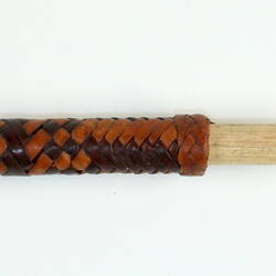 Wooden stick, half of which is covered with braided leather.
