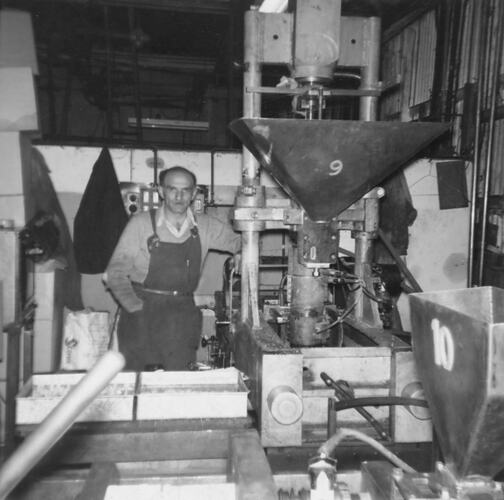 Man wearing overalls in factory environment.