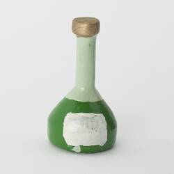 Miniature green and white champagne-style bottle from a doll's house.