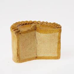 Brown round pie, section cut out. Miniature model. Profile.