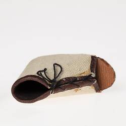 Miniature white canvas prosthetic open toe lace-up shoe. Black rubber sole. Top view.