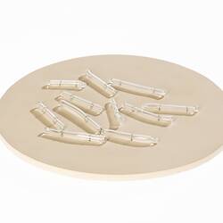 Light brown disc with clear glass capsule-shaped pieces on top.