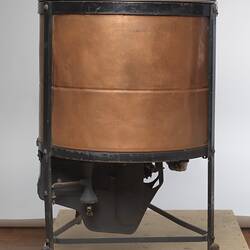 Washing machine with one large copper barrel and one smaller one connected at the base by a metal frame.
