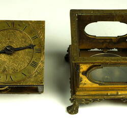 Decorative table clock. Mechanism removed and sat beside square gilded brass case on four feet.
