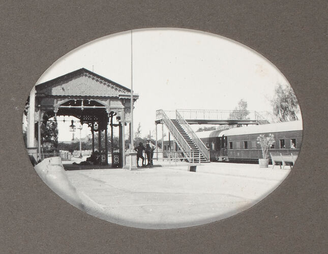 Railway station with train and soldiers standing around.