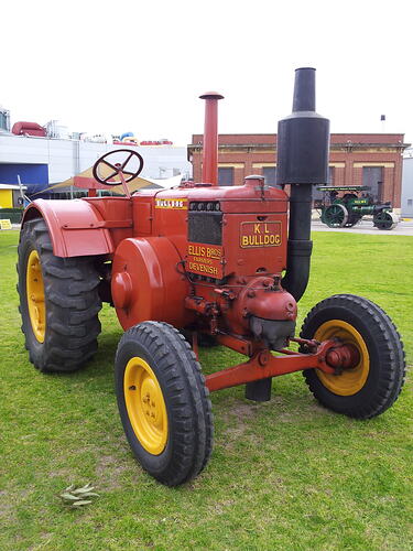 Tractor parked on arena, front left side view.